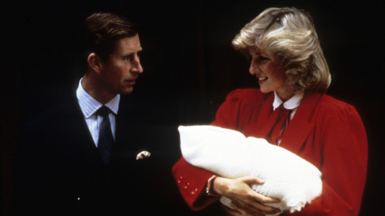 Prince Charles and Princess Diana holding Prince Harry 