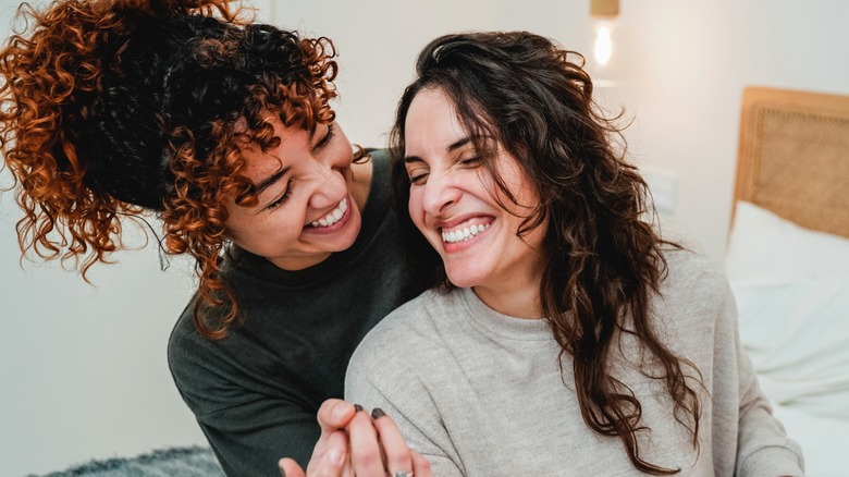 lesbian couple smiling in bed together 