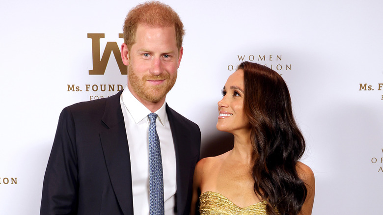 Prince Harry and Meghan Markle smiling on the red carpet