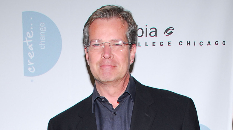 Steve Kmetko posing on a red carpet in front of a light grey background
