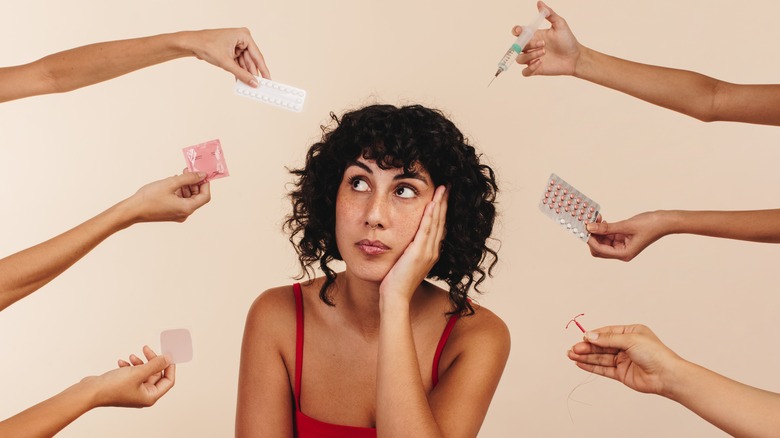 Hands holding contraceptives surrounding woman