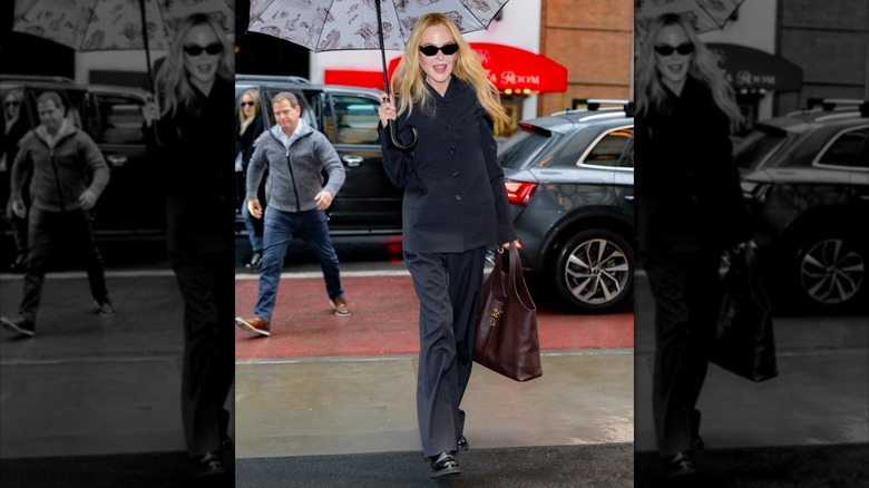 Nicole Kidman pictured in Midtown in New York City, wearing a gray outfit and holding an umbrella and a brown bag, while wearing sunglasses