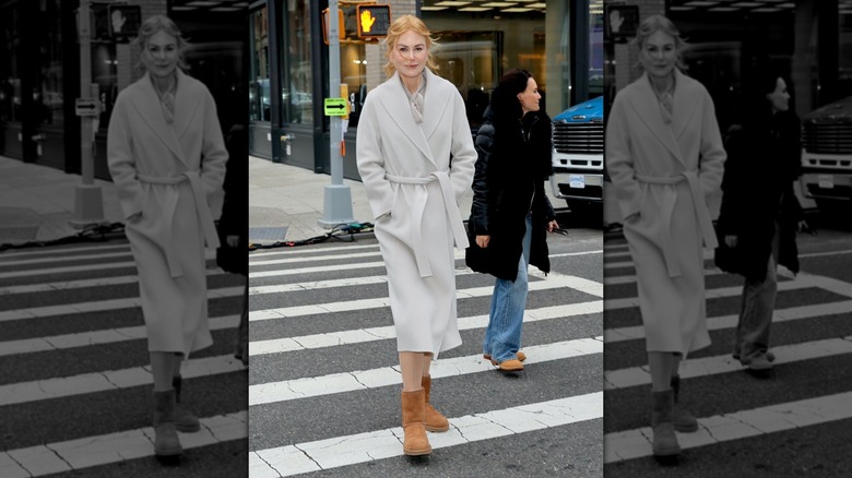 Nicole Kidman pictured on location in New York City at a crosswalk wearing a gray trench coat and UGGs