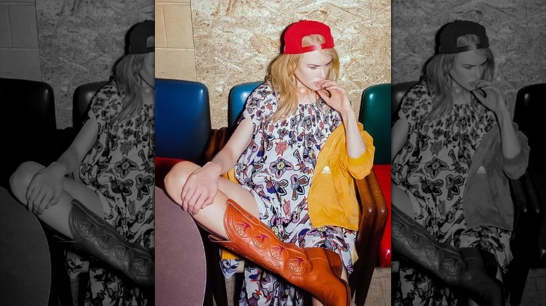 Nicole Kidman pictured at a bar in Nashville, Tennessee, wearing a short dress, brown cowboy boots, red cap, and yellow rain jacket