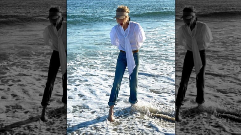 Nicole Kidman on the beach in Australia wearing a visor, white shirt, and jeans