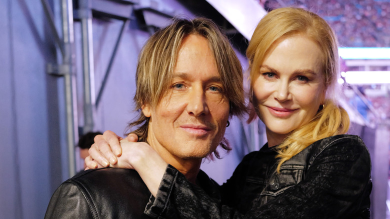 Keith Urban smiles while posing with Nicole Kidman as she puts her arms around him
