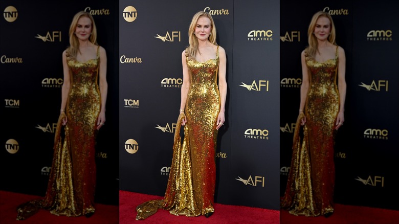 Nicole Kidman in a gold sequined dress holding the train accepting arriving for her Lifetime Achievement Award