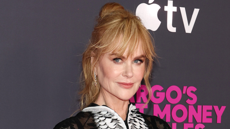 Nicole Kidman smiling while posing at an event with her hair in an updo