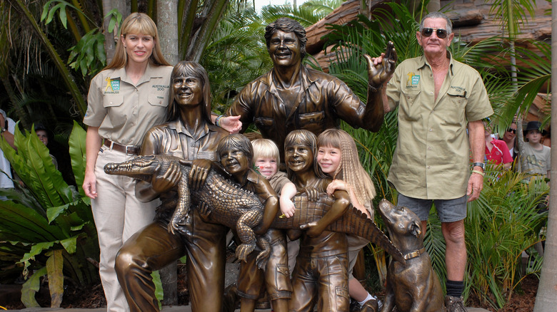 Terri Irwin, Robert Irwin, Bindi Irwin, and Bob Irwin posing with a statue depicting Steve Irwin and his family