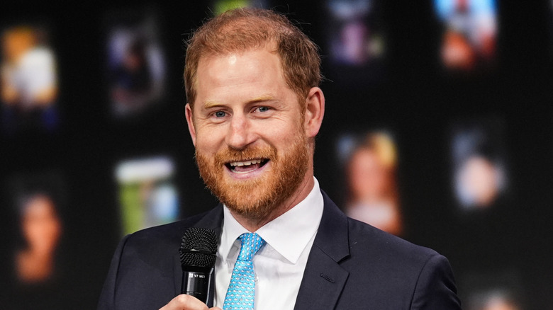 Prince Harry smiling and holding microphone