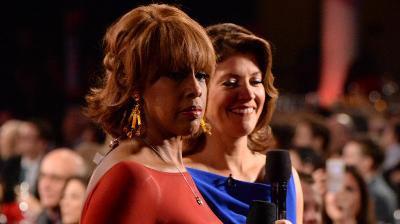 Gayle King looking miffed next to a smiling Norah O'Donnell