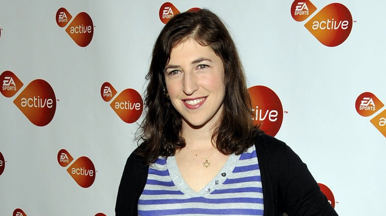 Mayim Bialik smiling and wearing casual clothing at a red carpet event.