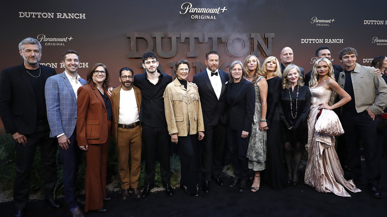 The cast and crew of 'Dutton Ranch' posing in front of a promotional backdrop