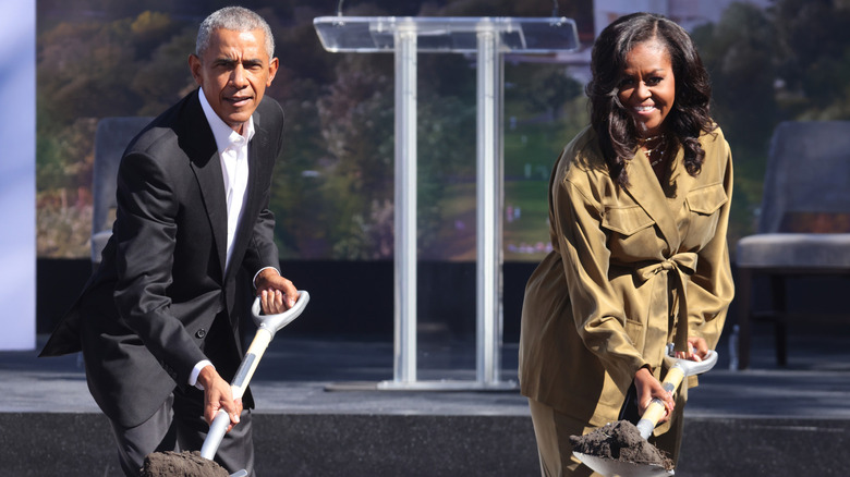 Barack and Michelle Obama using shovels in front of a podium