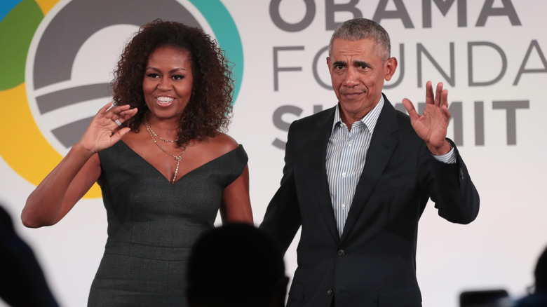 Michelle and Barack Obama waving onstage at an event