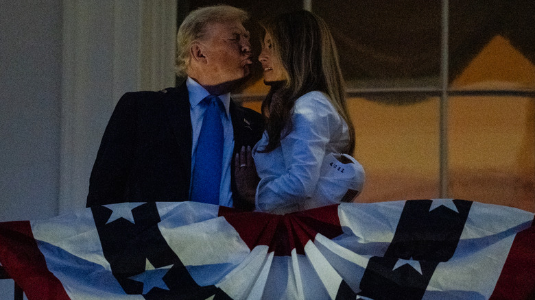 Donald Trump leaning in for a kiss with Melania Trump seemingly pushing him away on a balcony