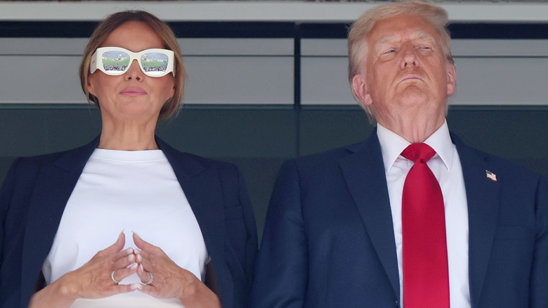 Melania Trump and Donald Trump standing next to each other looking grumpy
