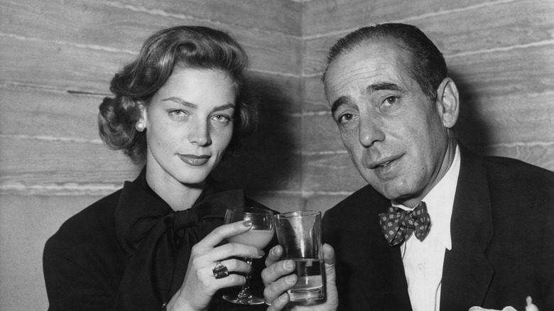 Humphrey Bogart and Lauren Bacall clinking glasses.