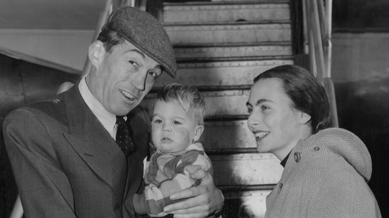 John Huston and Enrica Soma smiling with their baby Walter.