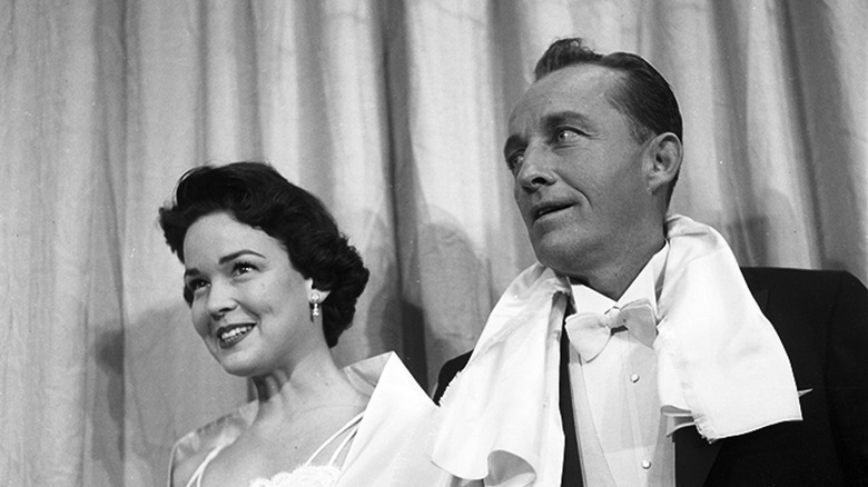 Kathryn Grant and Bing Crosby smiling against a curtain backdrop.