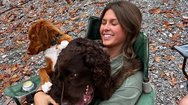 Ella Langley hugging dogs on a fold-out chair back home for Thanksgiving