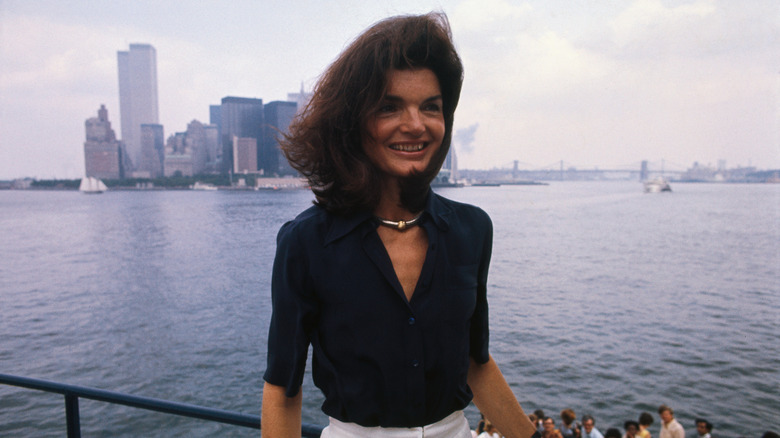Jacqueline Kennedy poses near Manhattan wearing a black shirt and silver necklace