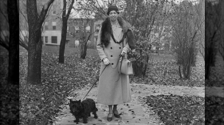 Eleanor Roosevelt walking a Scottish Terrier while wearing a stylish trench coat and a mink stole