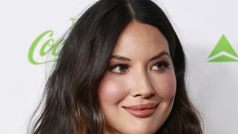 Olivia Munn smiling at event with long wavy hair