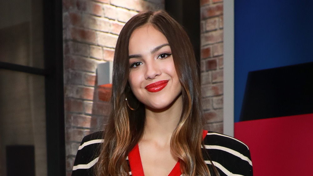 Olivia Rodrigo smiling with red lipstick