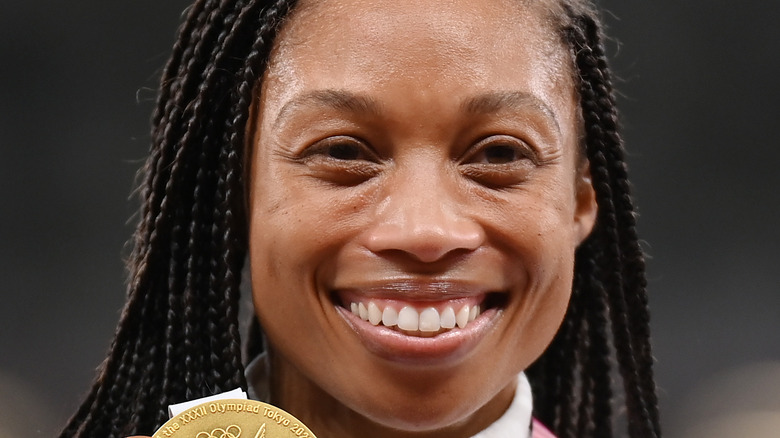 Allyson Felix smiling while holding up her gold medal