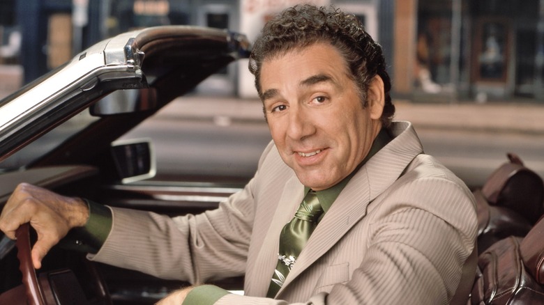 Michael Richards smiling and posing in a car in 2000