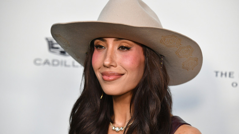 Cheryl Burke in a cowboy hat and heavy blush on a Cadillac sponsored red carpet in 2026