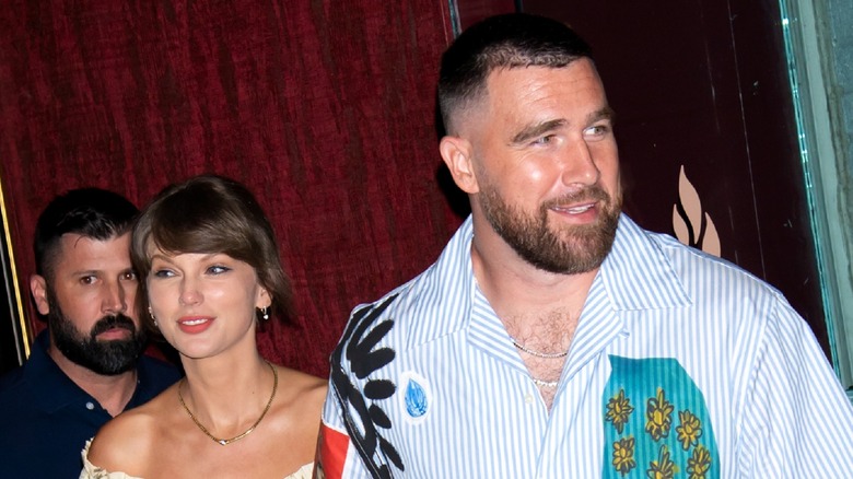 Taylor Swift and Travis Kelce smiling and walking