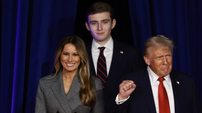 Melania and Barron Trump smiling and Donald Trump grimacing