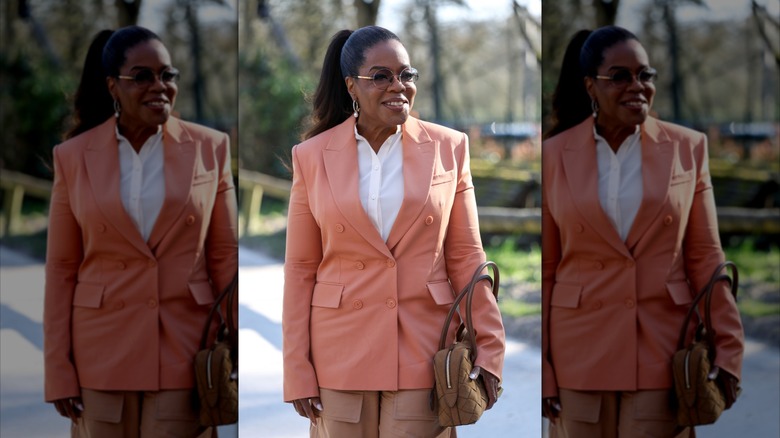 Oprah Winfrey smiling and posing in an orange suit.