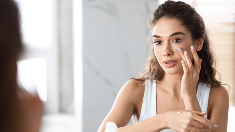 woman applying concealer makeup