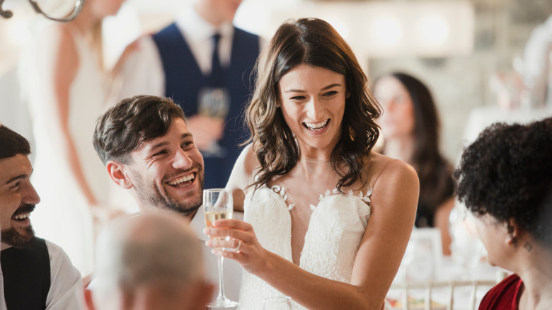 Happy bride gives a toast surrounded by guests