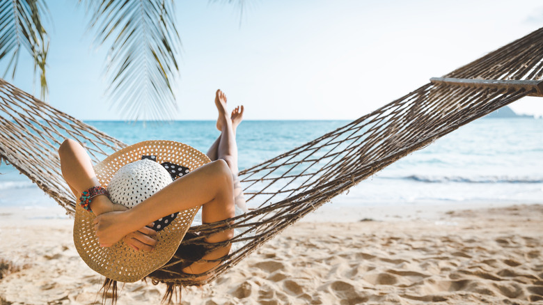 Woman relaxes in hammock on beach