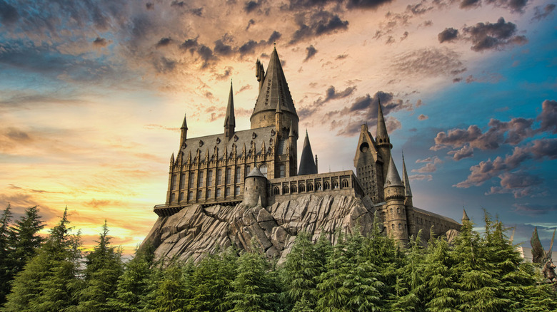 Hogwarts castle sitting on a hill with a sunset behind it