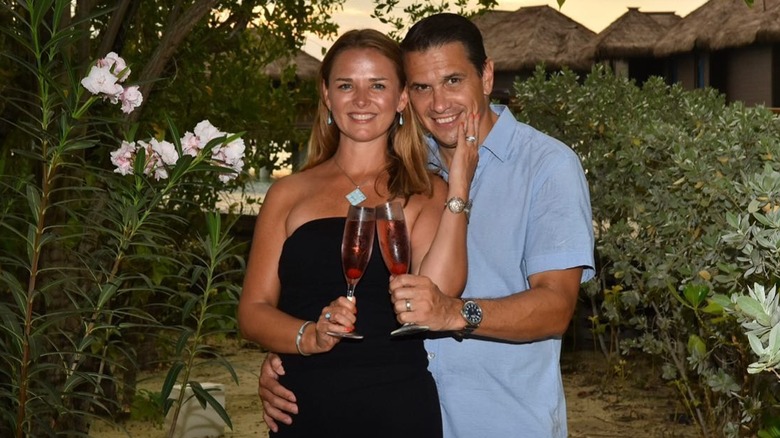 Todd holding Kristine Blanche at the hip while clinking flutes together