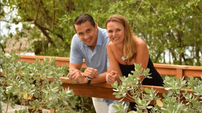 Kristine and Todd Blanche leaning over a leafy railing side by side
