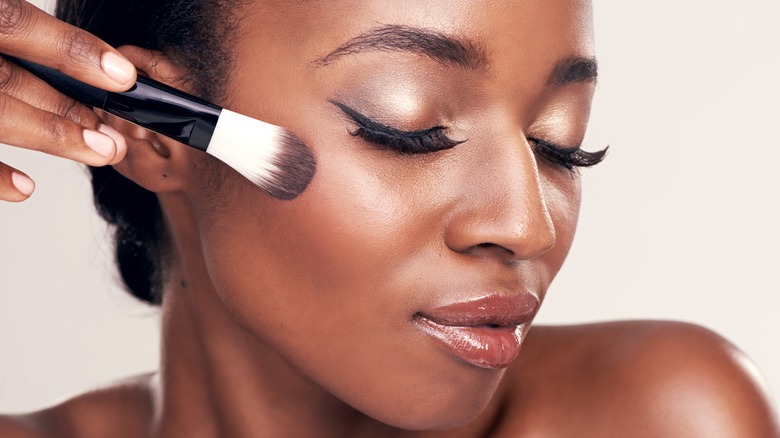 Woman applying powder blush to cheeks