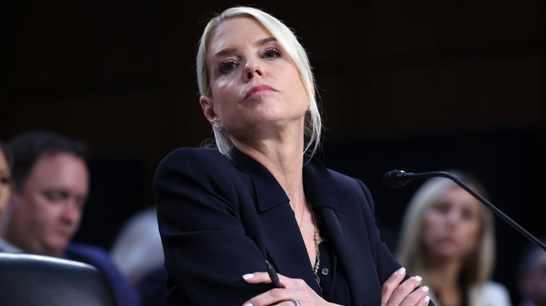 Pam Bondi looking serious as she sits in front of microphone