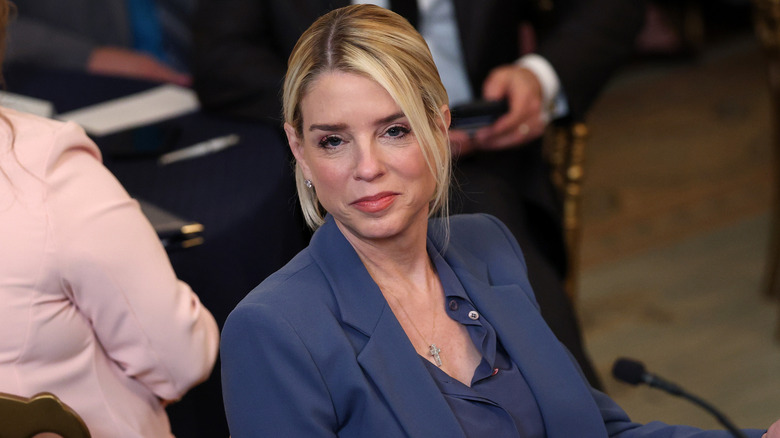 Pam Bondi smiling at camera while sitting in front of microphone