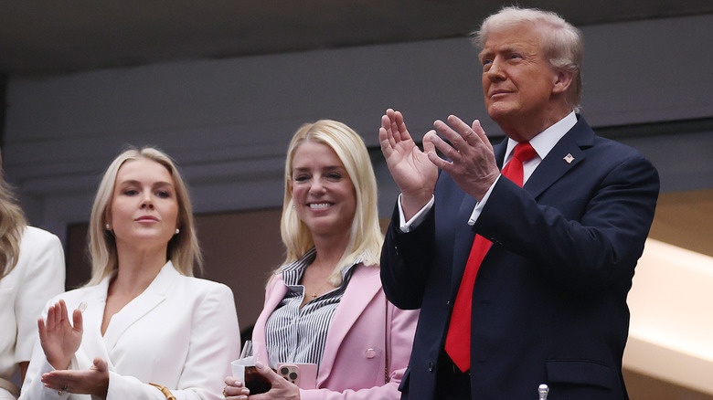 Karoline Leavitt, Pam Bondi, and Donald Trump clapping and addressing a crowd
