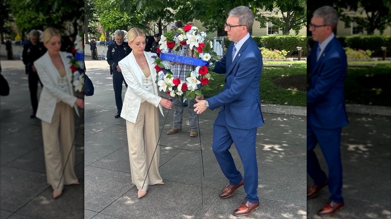 Pam Bondi looking down as she and a man position a wreath