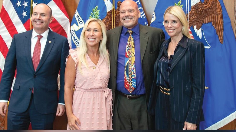 Pam Bondi, Marjorie Taylor Greene, Dr. Kirk Moore in front of flags
