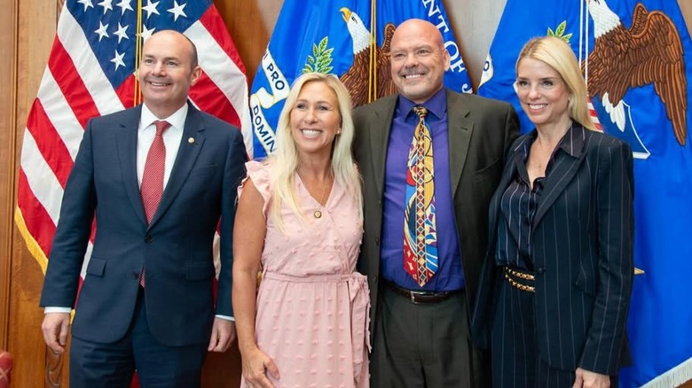 Pam Bondi smiling with Marjorie Taylor Greene while wearing a black pin-striped suit.