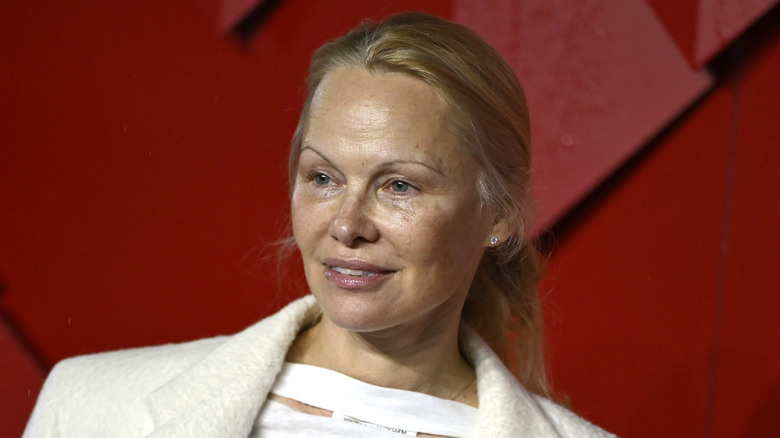 Pamela Anderson posing at an event with her hair pulled back