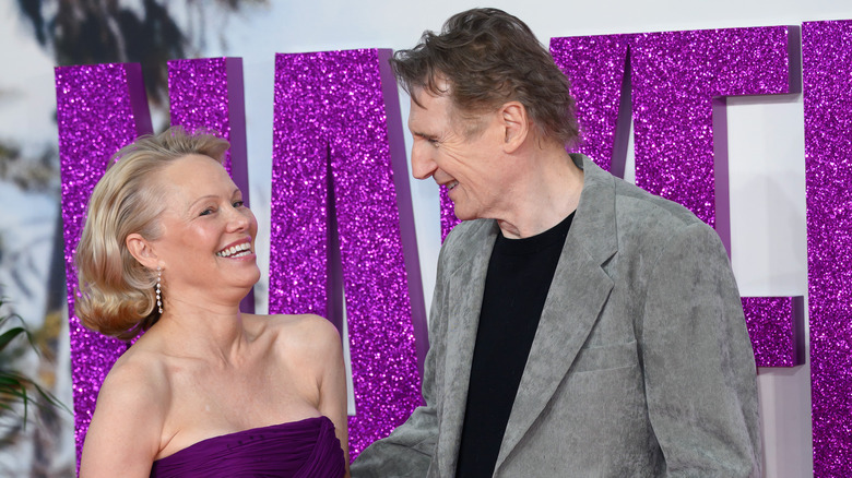 Pamela Anderson laughing while Liam Neeson talks to her